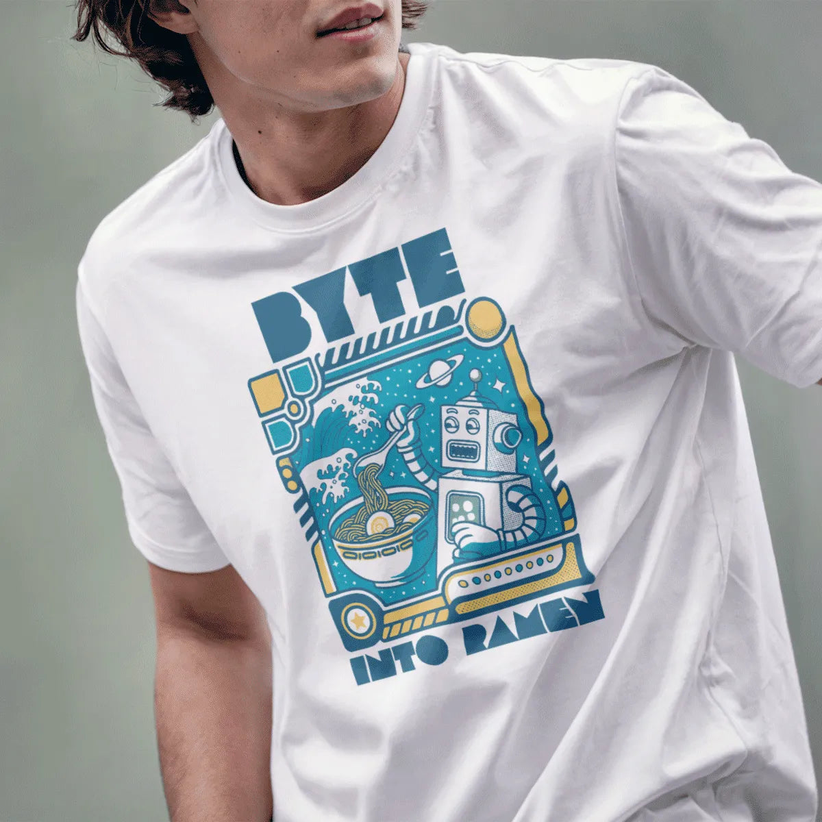 Male model in white t-shirt with robot ramen design, blue and yellow colors, and playful robot.
