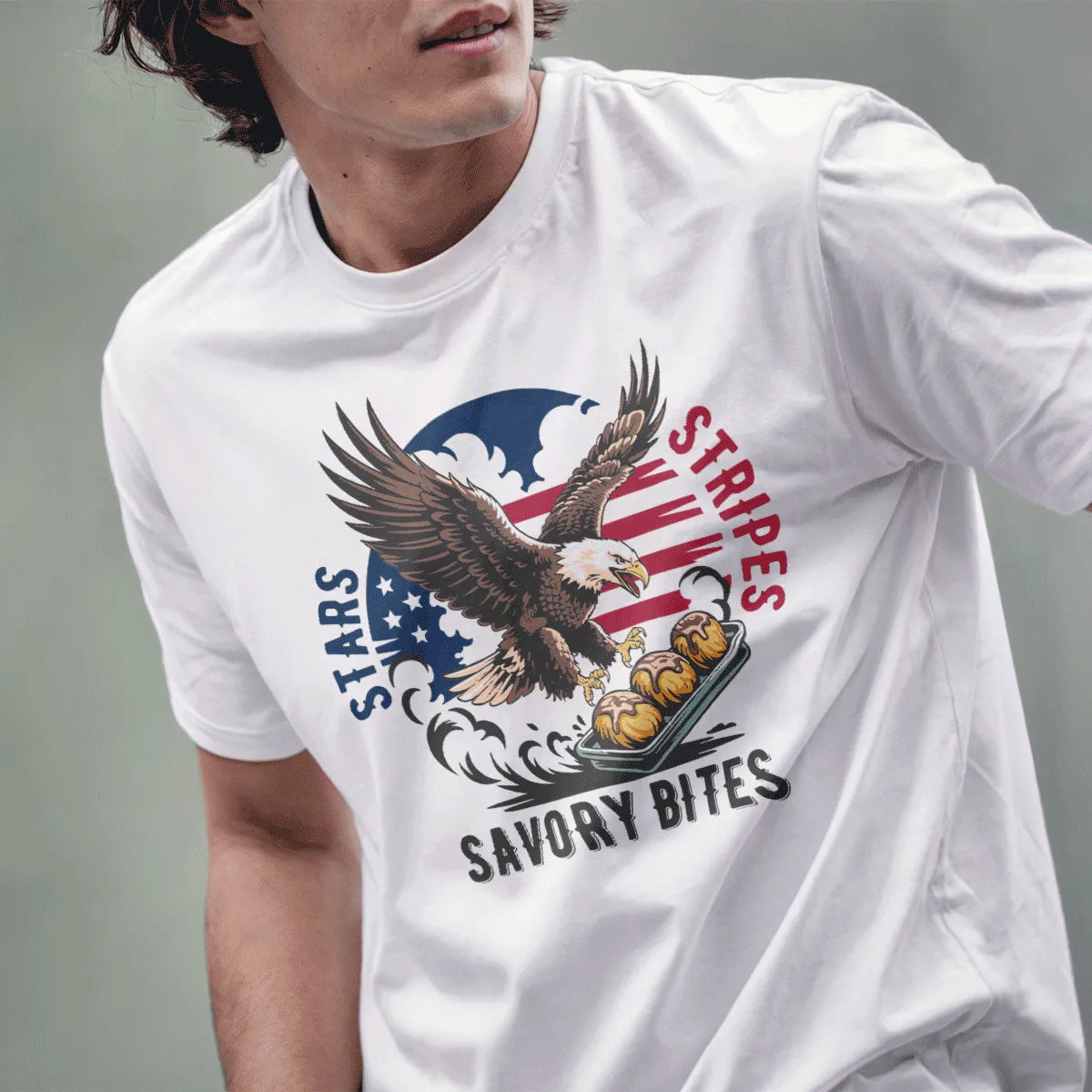 Male model wears white t-shirt featuring powerful eagle, savory bites tray, and stars and stripes background.