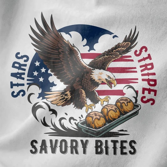 Close-up of white t-shirt fabric with detailed bald eagle, tray of takoyaki, and bold patriotic lettering.