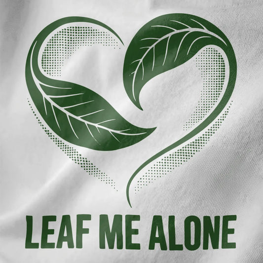 White fabric close-up reveals heart-shaped green leaves with “LEAF ME ALONE” phrase, nature and calming colors.